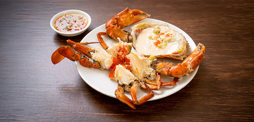A plated stone crab recipe, served with a side of sauce